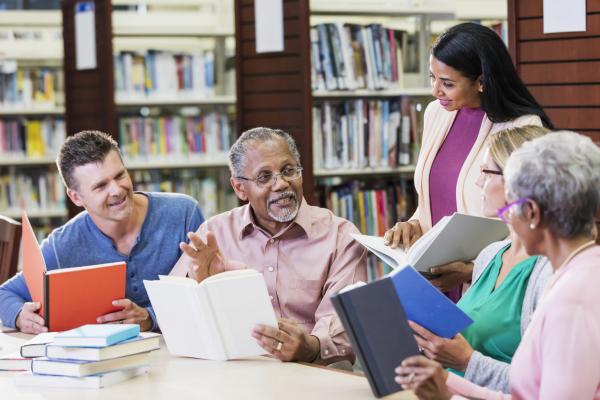 Adults discussing books in the library.