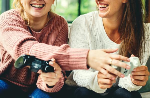 Two teenage girls with video game controllers, laughing